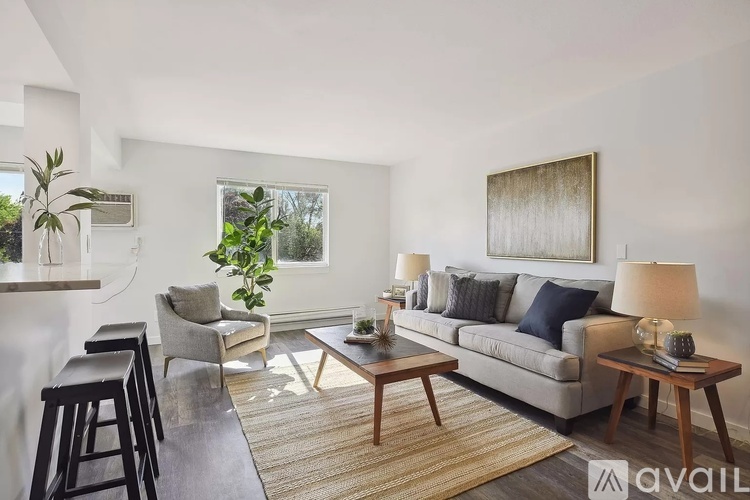 A living room with a grey couch, a wooden table, and a painting on the wall.