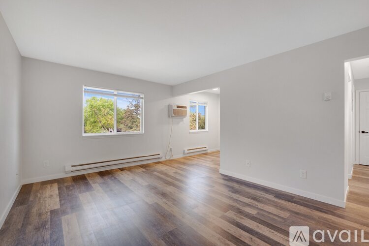 A room with wooden floors and a window showing trees outside.