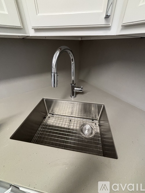 A kitchen sink with a chrome faucet and a grid drain.