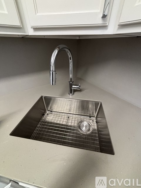 A kitchen sink with a chrome faucet and a grid drain.