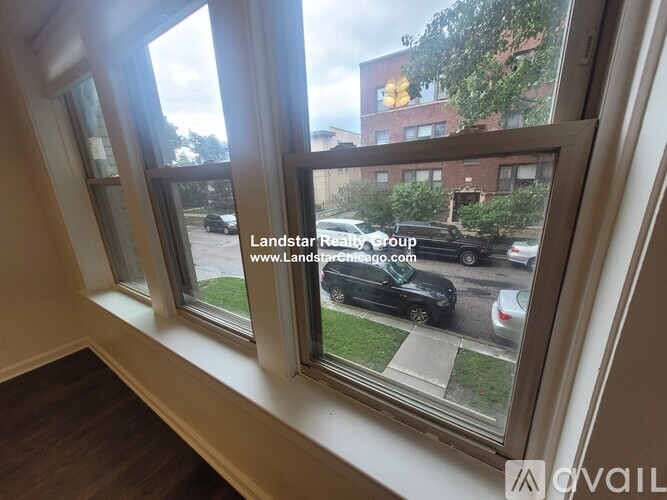 A window with a view of a street with cars and buildings.