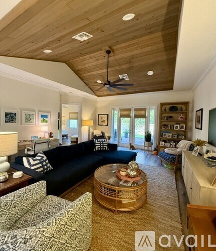 A living room with a black couch and a wooden ceiling.