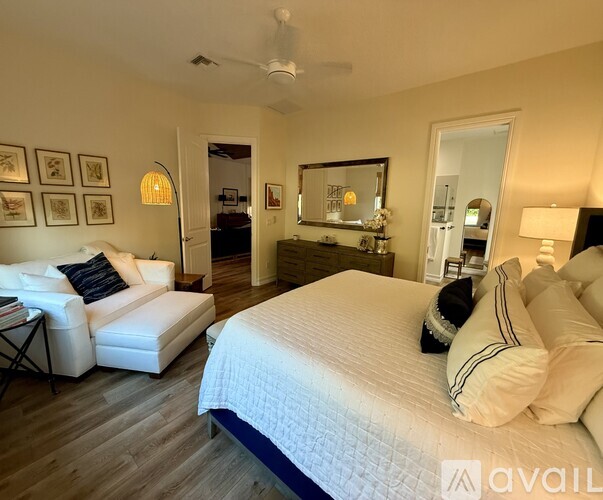 A bedroom with a large bed, a white couch, and a mirror on the wall.