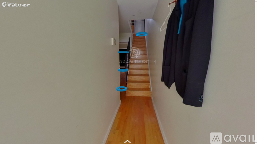 A hallway with a coat hanging on the wall and a staircase leading to the second floor.