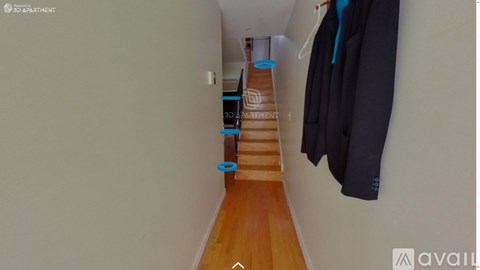A hallway with a coat hanging on the wall and a staircase leading to the second floor.