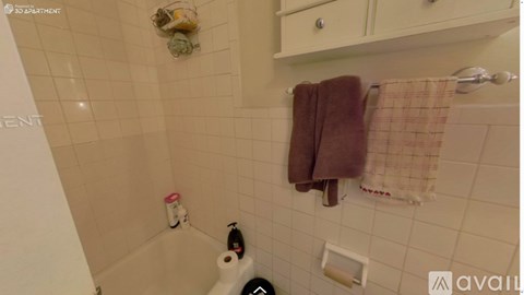 A bathroom with a toilet, a towel, and a shower.