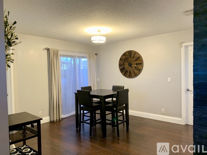 A dining room with a table and chairs and a clock on the wall.