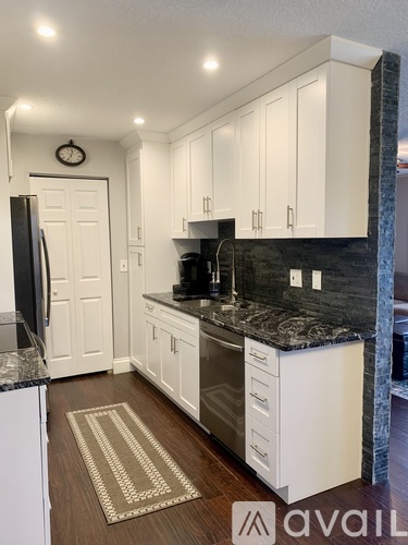 A kitchen with white cabinets and a black countertop.