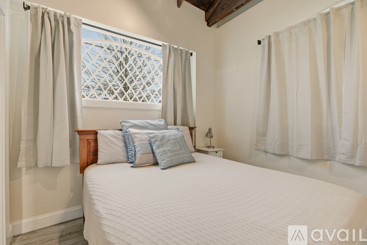 A bedroom with a large bed and a window with curtains.