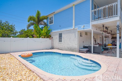 A small pool in a backyard with a blue house.