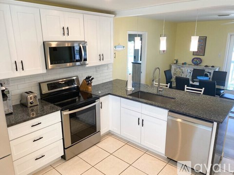 A kitchen with white cabinets and a granite countertop.