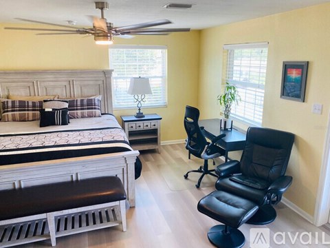 A bedroom with a bed, chair, and ceiling fan.