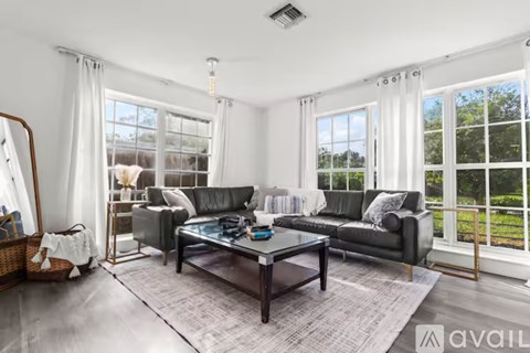 A modern living room with a glass coffee table and a large window.