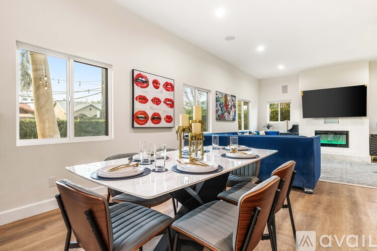 A dining room with a table set for two and a television in the corner.