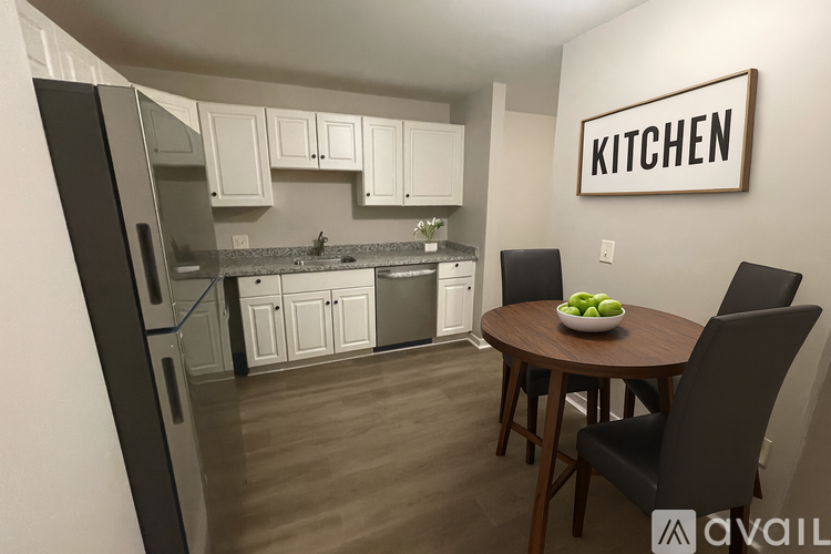 A kitchen with a refrigerator, sink, and a table with chairs.