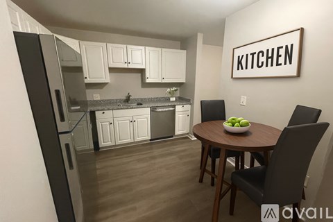 A kitchen with a refrigerator, sink, and a table with chairs.