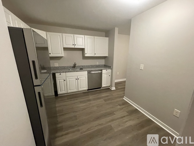 A kitchen with white cabinets and a black refrigerator.