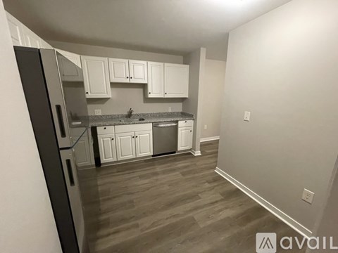 A kitchen with white cabinets and a black refrigerator.