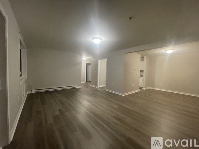A spacious room with wooden flooring and white walls.
