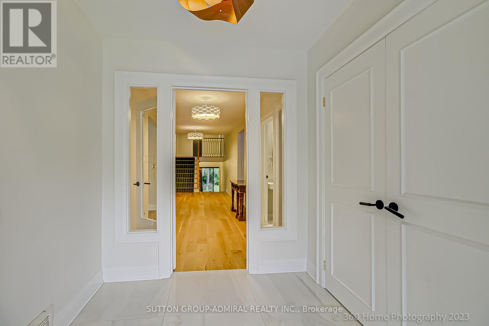 A hallway with a wooden floor and white walls leading to a bedroom.