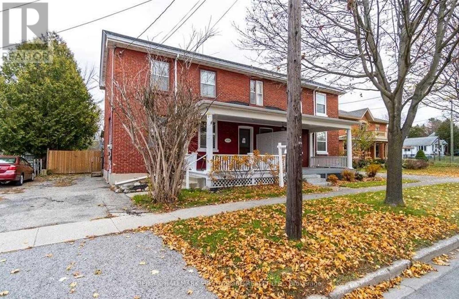 A red brick house with a white porch and a tree with yellow leaves.