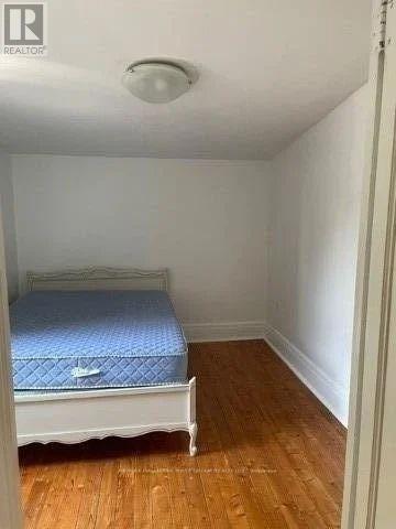 A bedroom with a bed and wooden floors.