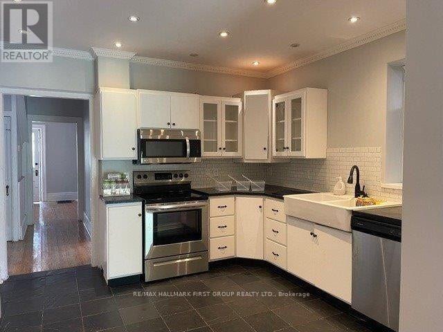 A kitchen with white cabinets and black countertops.