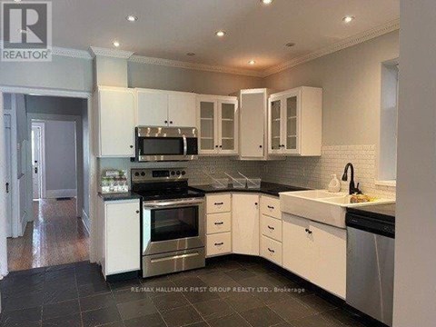 A kitchen with white cabinets and black countertops.