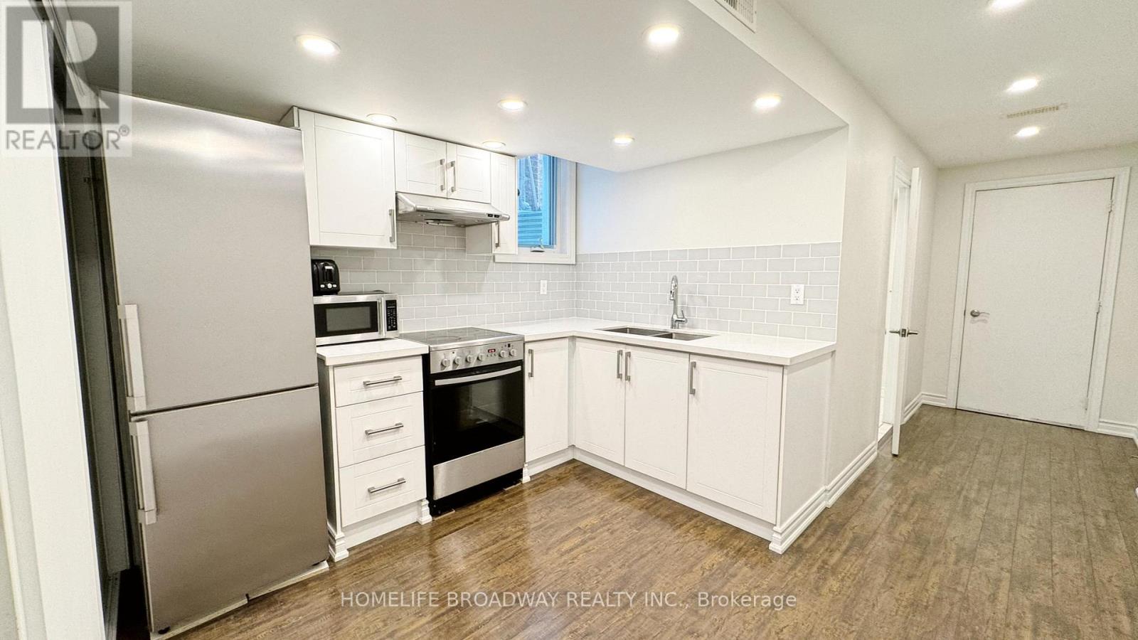 A kitchen with white cabinets and a stainless steel refrigerator.