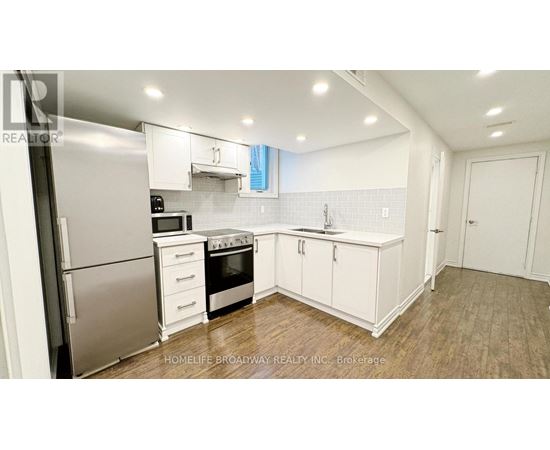 A kitchen with white cabinets and a stainless steel refrigerator.