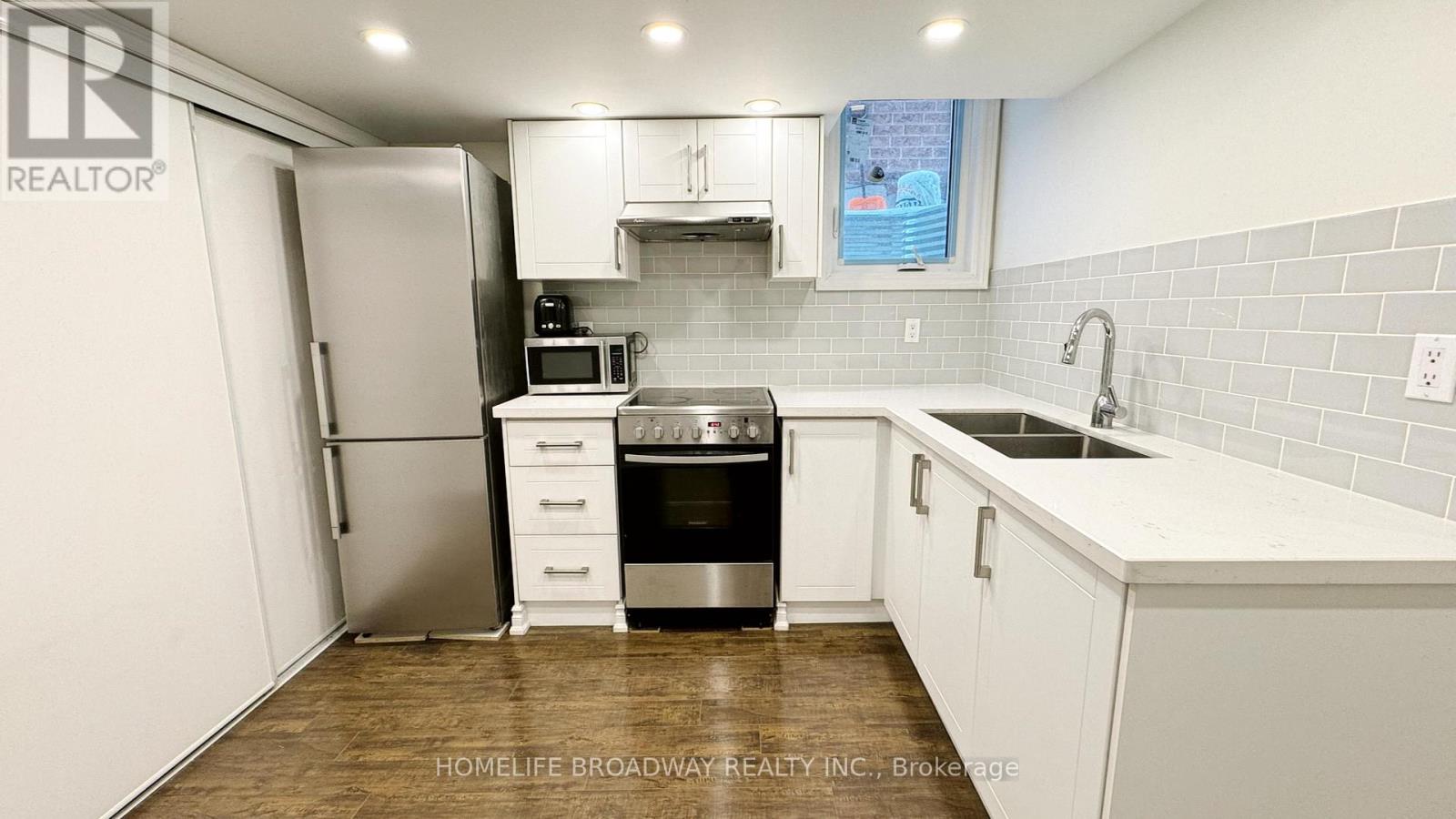 A kitchen with white cabinets and a wooden floor.