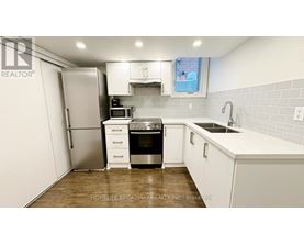 A kitchen with white cabinets and a wooden floor.