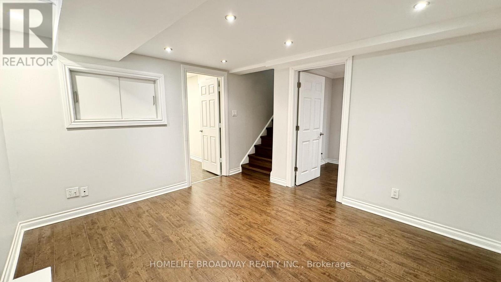 A spacious room with wooden flooring and white walls.