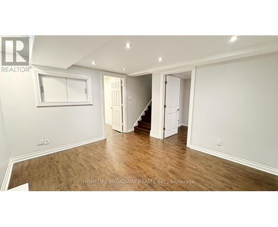 A spacious room with wooden flooring and white walls.