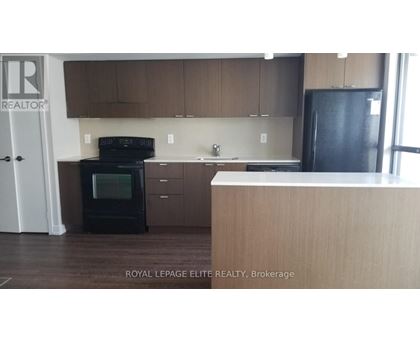 A kitchen with brown cabinets and a black fridge.