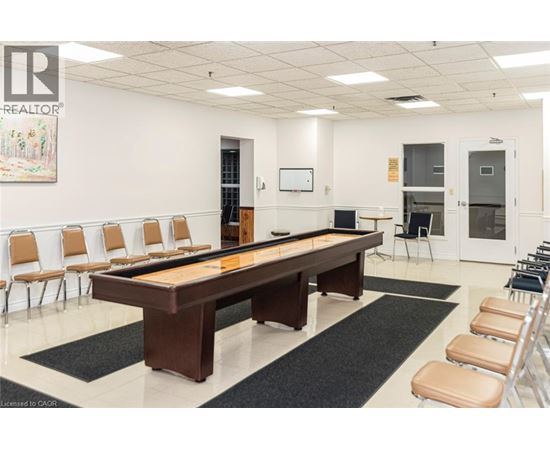 A room with a pool table and chairs.