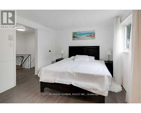 A bedroom with a large bed and a painting on the wall.