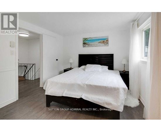 A bedroom with a large bed and a painting on the wall.