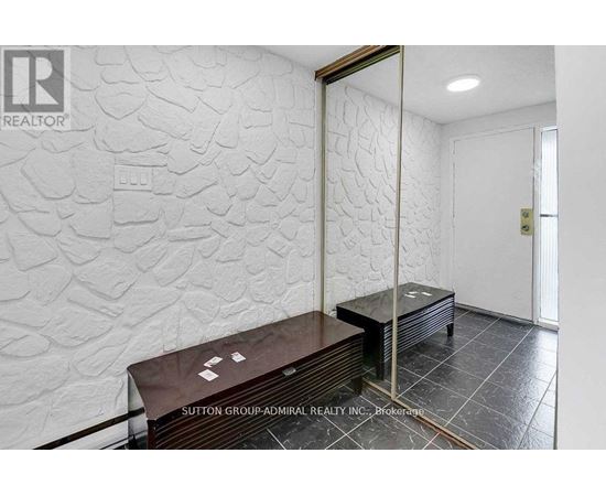 A room with a stone wall and a wooden bench.