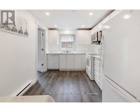 A kitchen with white cabinets and a wooden floor.