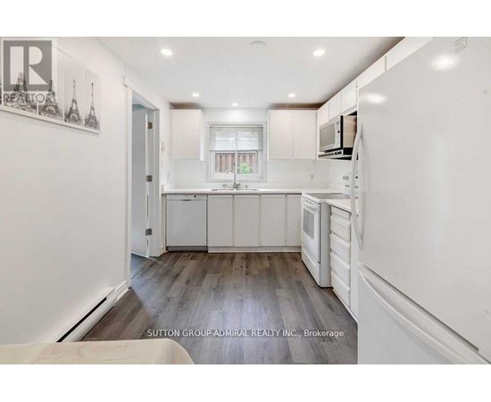 A kitchen with white cabinets and a wooden floor.