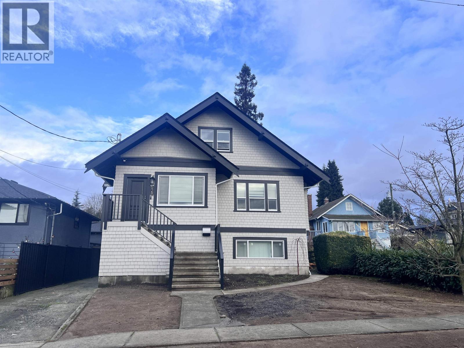 A house with a grey roof and a black fence is for sale.