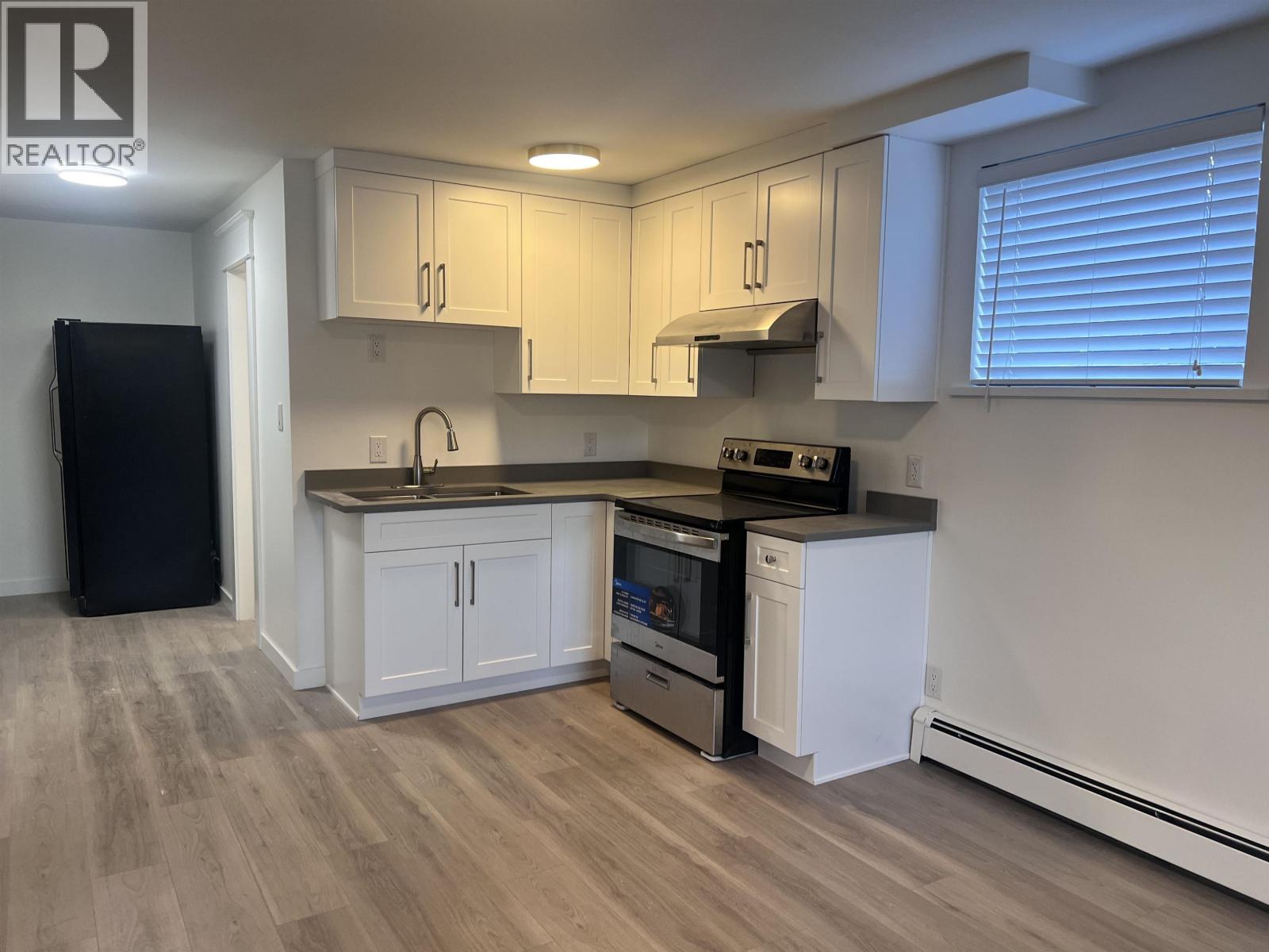 A kitchen with white cabinets and a black fridge.