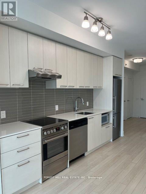 A modern kitchen with white cabinets and stainless steel appliances.