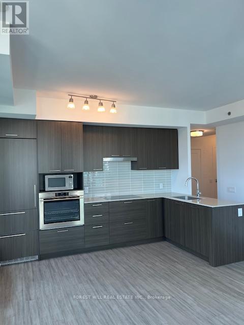 A modern kitchen with dark wood cabinets and a stainless steel oven.