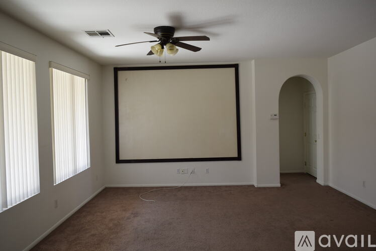 A room with a ceiling fan and a large empty wall.