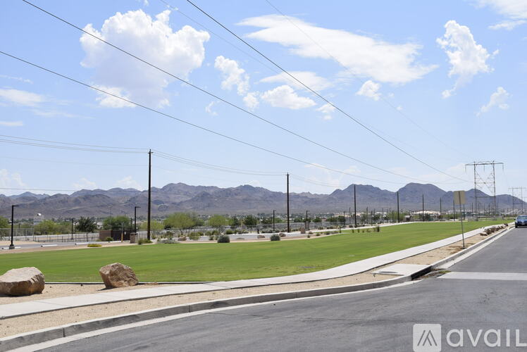 A road with a grassy area and mountains in the background.