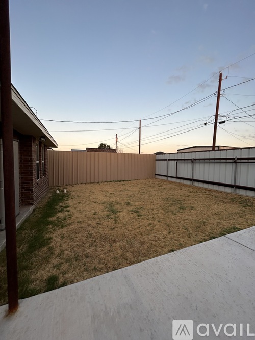 A backyard with a fence and a clear sky.
