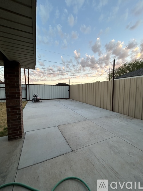 A backyard with a concrete patio and a fence.