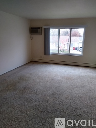 A room with a window and a carpeted floor.